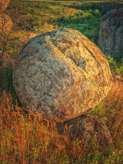 portrait view to huge round granite boulder in golden light of sun