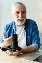 Senior man recording podcast using microphone and laptop