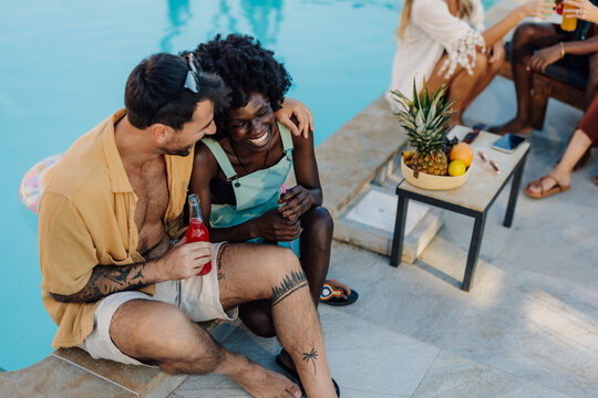 Happy multi ethnic couple embracing and having fun at pool party
