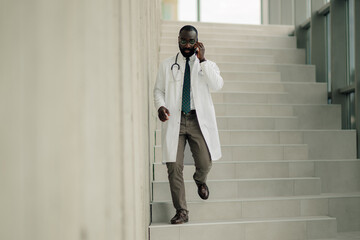 Doctor walking down stairs while talking on phone in hospital