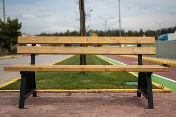 Profile view photo of a wooden bench in the park with nobody in it.