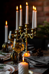 Rustic elegant table decor for christmas family dinner. Center piece with white candle, pine cone, fir tree branches. Zero waste eco-friendly home decoration. Cozy atmosphere, wooden background.