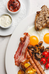 Delicious English Breakfast Fried Eggs, Sausage, Bacon, Tomatoes and Toast