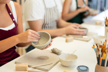 Female hands forming plate from wet clay in a pottery workshop