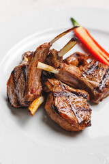 Grilled lamb chops with red chili on a white plate