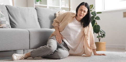 Young woman suffering from severe abdominal pain at home
