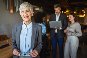Confident stylish caucasian mature businesswoman standing at workplace
