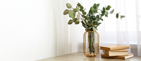 Books and vase with eucalyptus branches on table near window. Banner for design