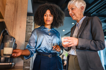 female colleagues chat while wait for coffee on a modern coffee machine