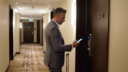 Businessman standing, at hotel door with phone man in suit accessing room showing corporate travel hospitality and modern keyless entry with digital check in - Powered by Adobe