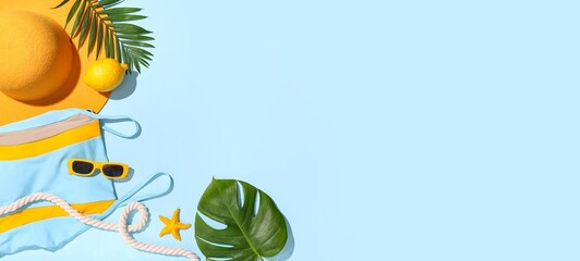 Composition with swimsuit, beach accessories and tropical leaves on light blue background with...