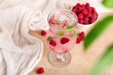 Glass of fresh raspberry mojito and bowl with berries on pink background