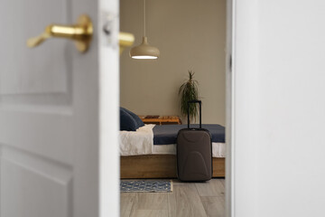 View of hotel room with suitcase and bed through open door