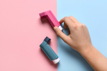 Child's hand with asthma inhalers on color background
