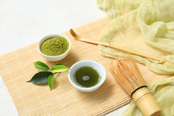 Bowls of matcha tea and powder with chasen on white background