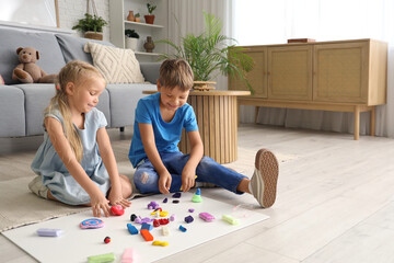 Little children sculpting from plasticine on floor at home