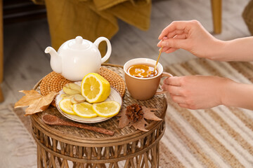 Female hands stirring green tea on table in room