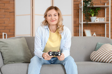 Beautiful young woman playing video game on sofa at home