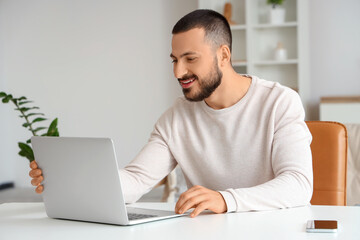 Fototapeta premium Handsome man working with laptop at home