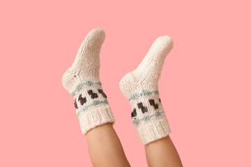 Legs of young woman in knitted socks on pink background