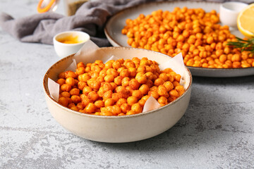 Bowl and plate with tasty fried chickpeas on grey background