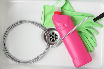 Sink with clogged drain, plumber's snake and rubber gloves, top view