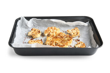 Baking dish with baked cauliflower steaks on white background