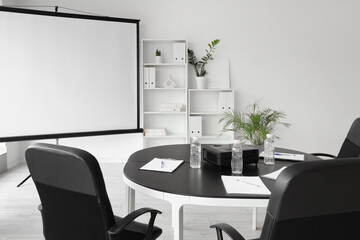 Interior of conference hall with blank projector screen and table