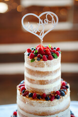 wedding cake, rustic wedding, naked cake, three-tier cake, berries, fresh fruit, celebration, wedding dessert, cake table, wood decor, romantic, countryside wedding, heart topper, bride and groom, cha