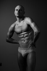 Fototapeta premium Black and white image of a muscular man posing confidently, showcasing strong physique and expression. The composition emphasizes fitness and strength.