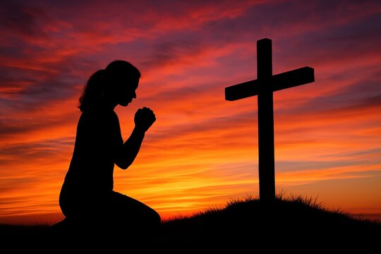 Silhouette of a solitary woman kneeling in prayer before a simple wooden cross on a grassy hilltop against a dramatic sunset sky symbolizing faith hope and spiritual devotion. - Powered by Adobe