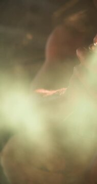 Vertical video: Young man in grunge studio playing electric guitar, lost in music