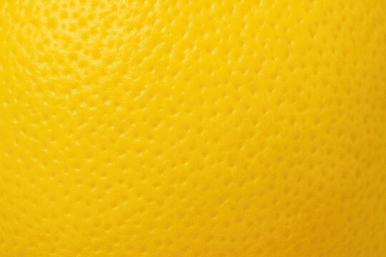 Yellow lemon peel macro showing bright color and detailed bumpy texture of citrus skin

