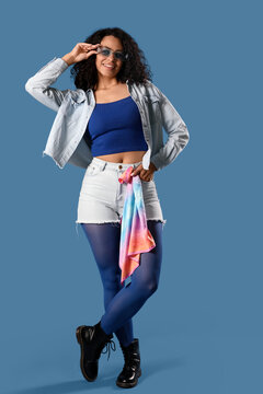 Fototapeta Stylish young African-American woman in sunglasses on blue background