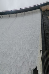 People gather to witness the spectacular sight of a dam spillway releasing torrents of water, a display of natural power.  Upper Nihotupu Reservoir, Auckland, New Zealand