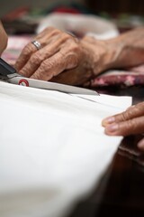 Elderly seamstress. Hands working in sewing, measuring, cutting, sewing by hand. Elderly woman seamstress