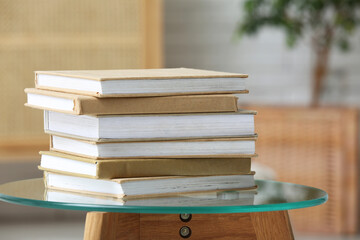 Stack of different books on glass table indoors