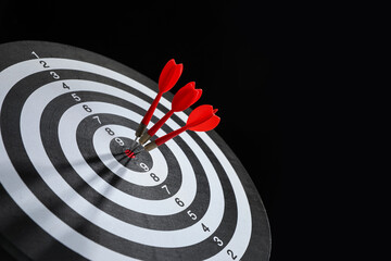 Targeting. Dart board with arrows on black background, closeup. Space for text