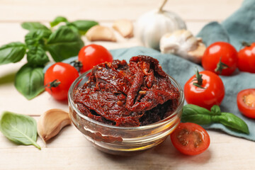 Delicious sun dried tomatoes, fresh vegetables, basil and garlic on white wooden table, closeup