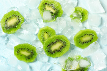 Ice cubes with slices of fresh kiwi on light blue background