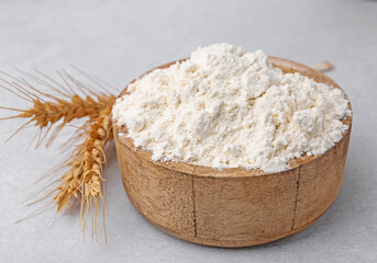 Wheat flour and spikes on white table, closeup