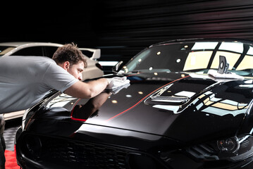 Trabajador Car detailing aplicando cera a automovil de color negro brillante