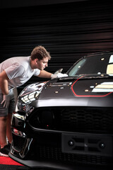 Trabajador Car detailing aplicando cera a automovil de color negro brillante