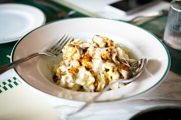 Truffle pasta with mushrooms is served on a white plate with a a spoon and fork.