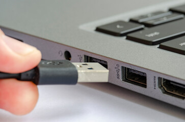 USB being plugged into laptop highlighting risk of unauthorized data transfer or malware