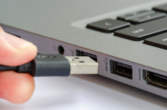 USB being plugged into laptop highlighting risk of unauthorized data transfer or malware