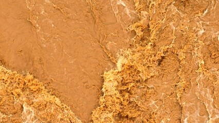 Drone aerial view of muddy floodwaters rushing over rocks, illustrating the impact of greenhouse...