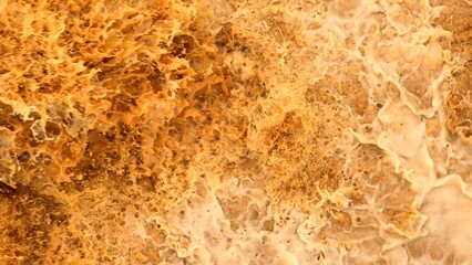 Drone aerial view of turbulent, sediment-laden floodwaters crashing over rocks, illustrating the...