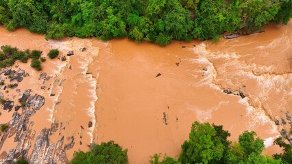 Drone shot shows floodwaters overflowing and churning near forest edges, illustrating natural...