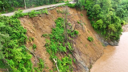 Aerial drone view of a slope failure adjacent to a river, demonstrating the combined effects of heavy rainfall and deforestation in triggering landslides and environmental degradation.
